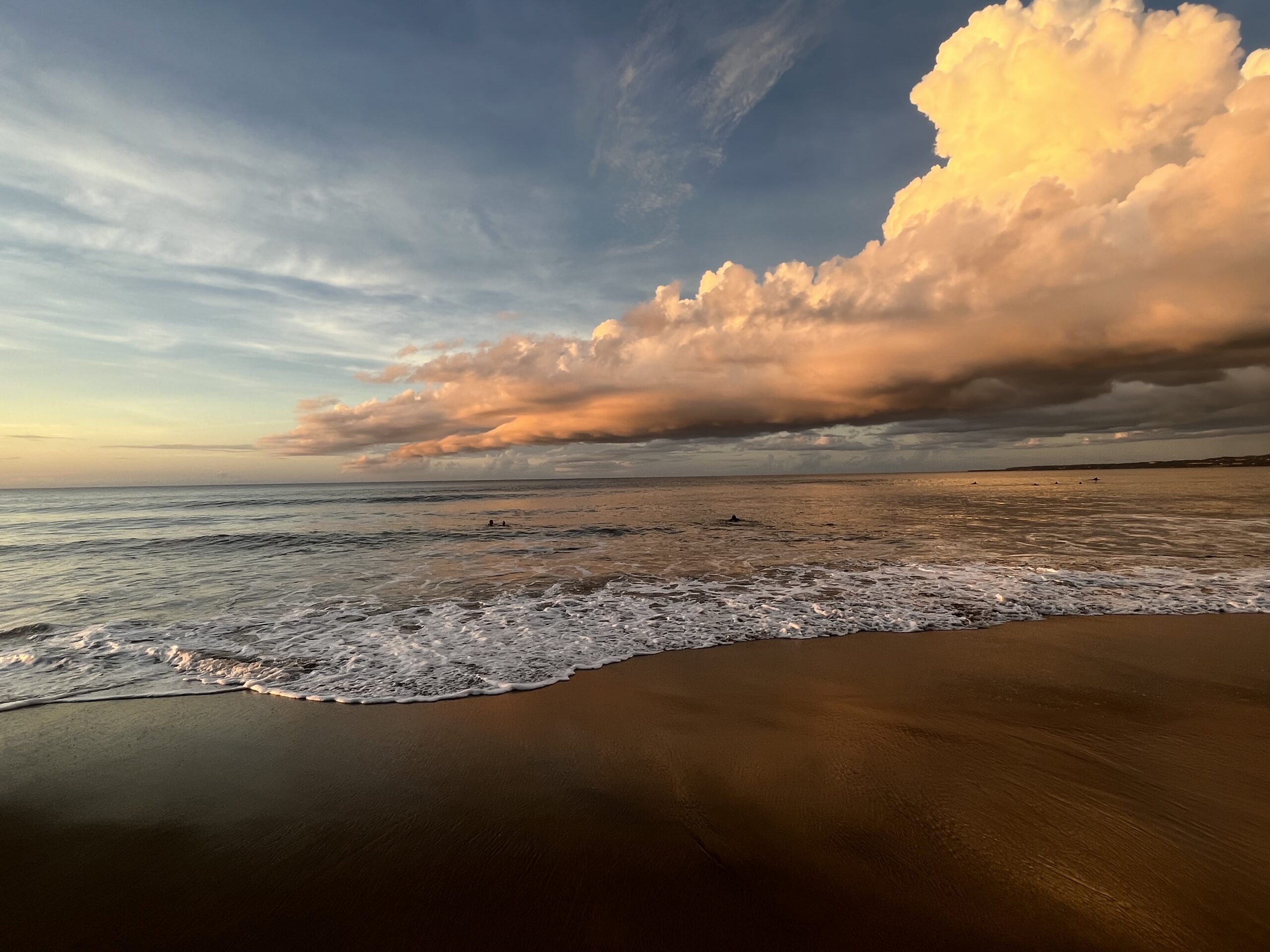 beach with water rolling in and cumulus cloud in the sky