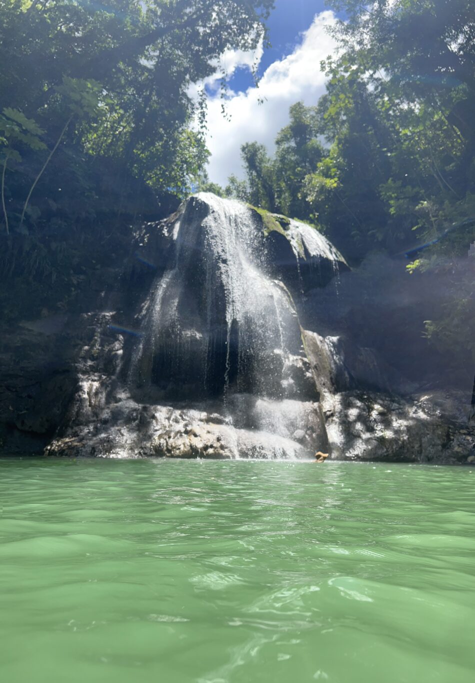 Waterfall over rocks into green pool in Puerto Rico