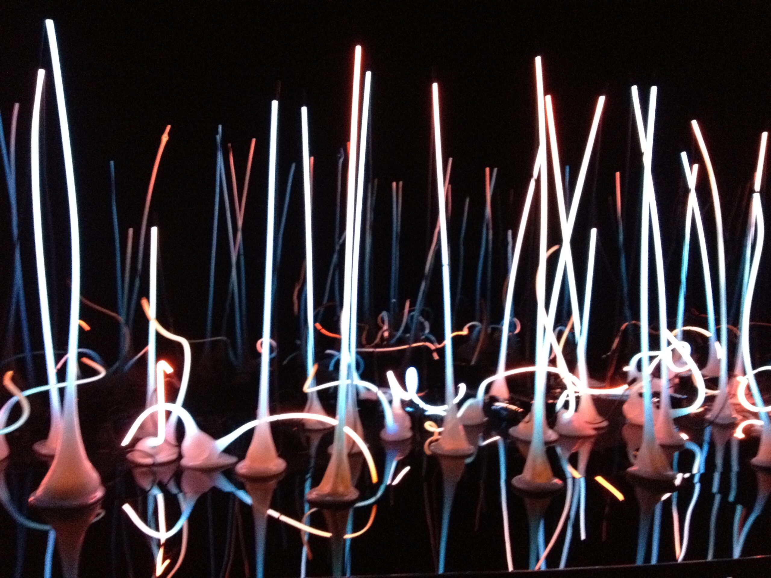 Pink and white tall glass sculptures against a black background